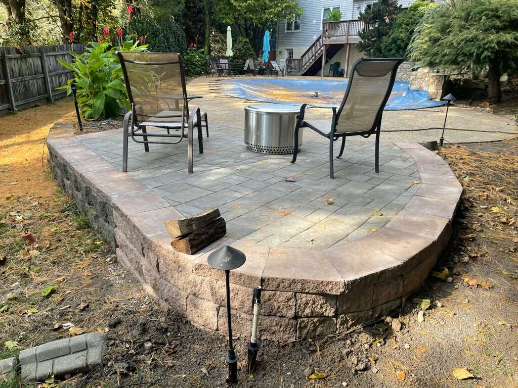 Curved paver patio with a fire pit, raised on a block retaining wall, in Chester County PA
