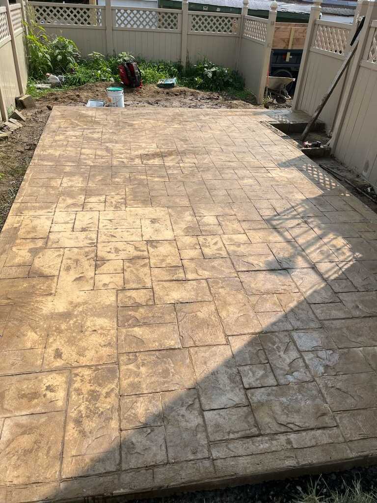 Large tan ashlar stamped concrete patio in a fenced back yard in West Chester, PA