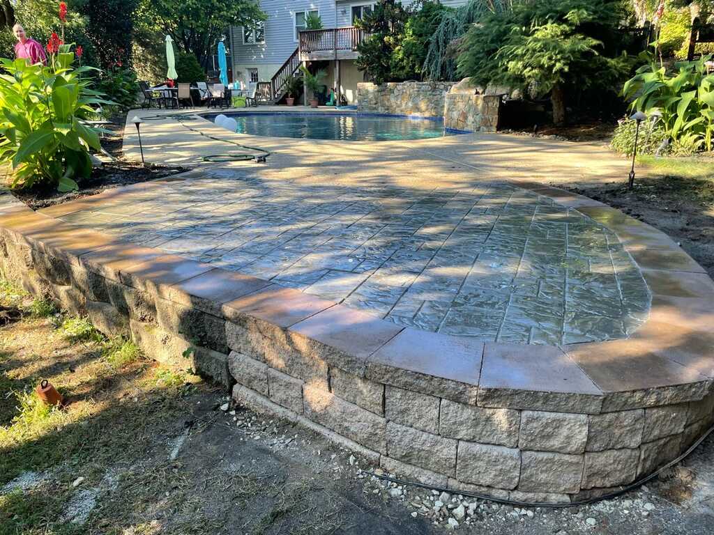 Stamped concrete pool deck with a segmental block retaining wall on a West Chester, PA property