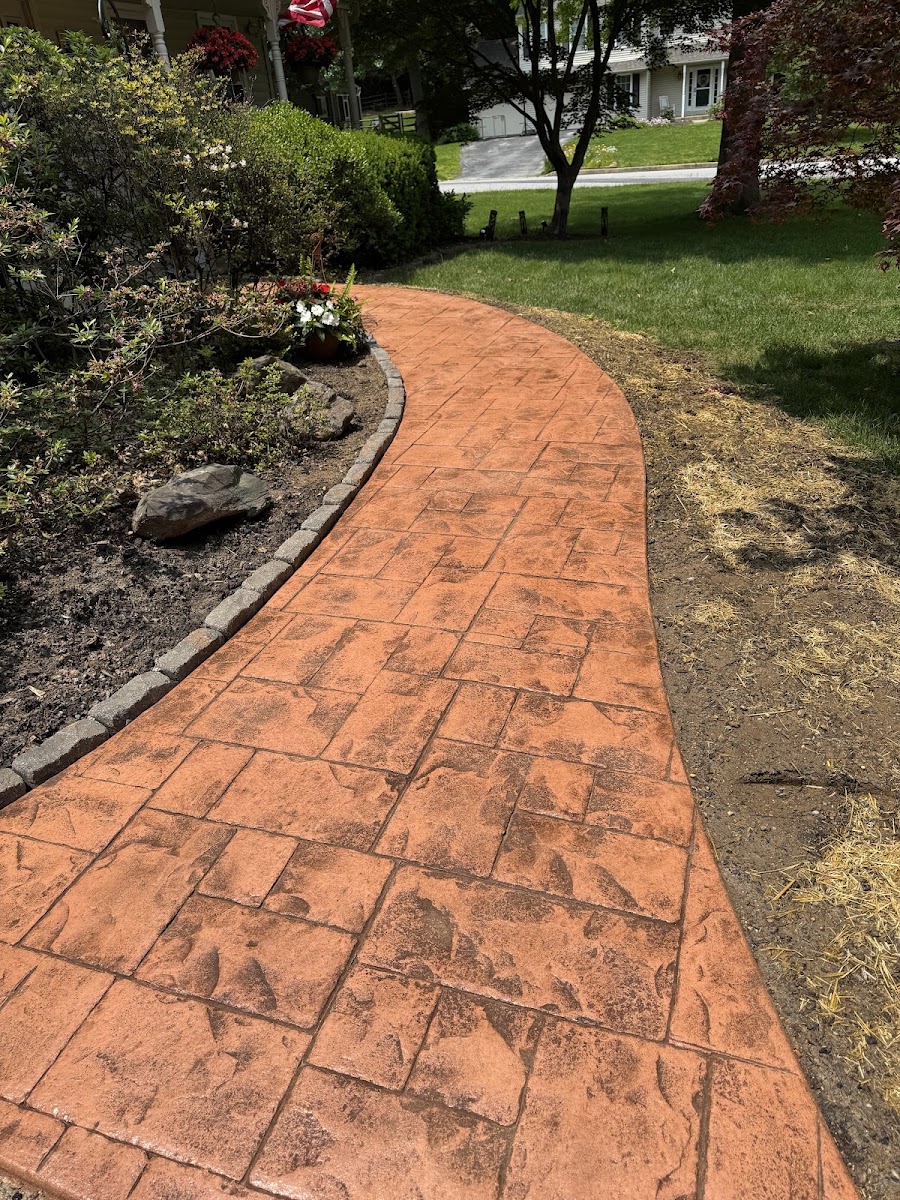 Curved terracotta stamped concrete front walkway with a cobble border in West Chester, PA